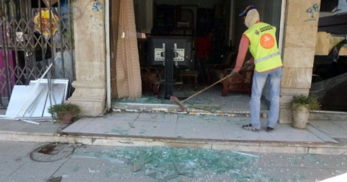 Ірак, Багдад. Працівник прибирає осколки скла від вітрини магазину, яку пошкодили під час нападів на поліцейські дільниці в Багдаді. В результаті підриву терористами двох автомобілів, начинених вибухівкою, загинули щонайменше 19 осіб. / © AFP