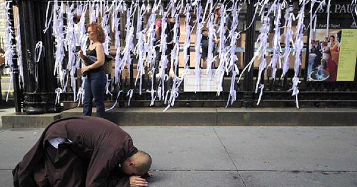 США, Нью-Йорк. Буддійський чернець молиться перед меморіальними "стрічками пам&#039;яті", які перехожі розвішують на паркані каплиці Святого Павла. Люди вшановують пам&rsquo;ять жертв теракту 9/11. Нью-Йорк готується до 10-ої річниці нападу на вежі Всесвітнього торгового центру. / © AFP