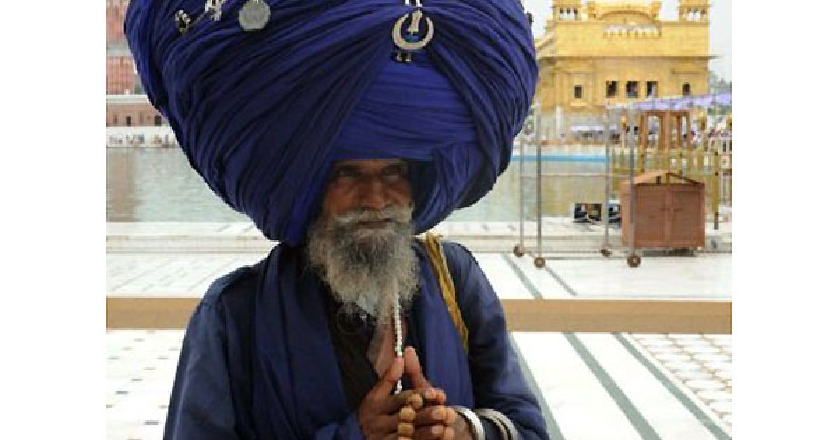 Індія, Амрітсар. Член сикхської армії Nihang, традиційних сикхських релігійних воїнів, несе на голові тюрбан, довжиною більше 300 м, під час ритуалу вшанування у Золотому храмі в Амрітсарі. / © AFP