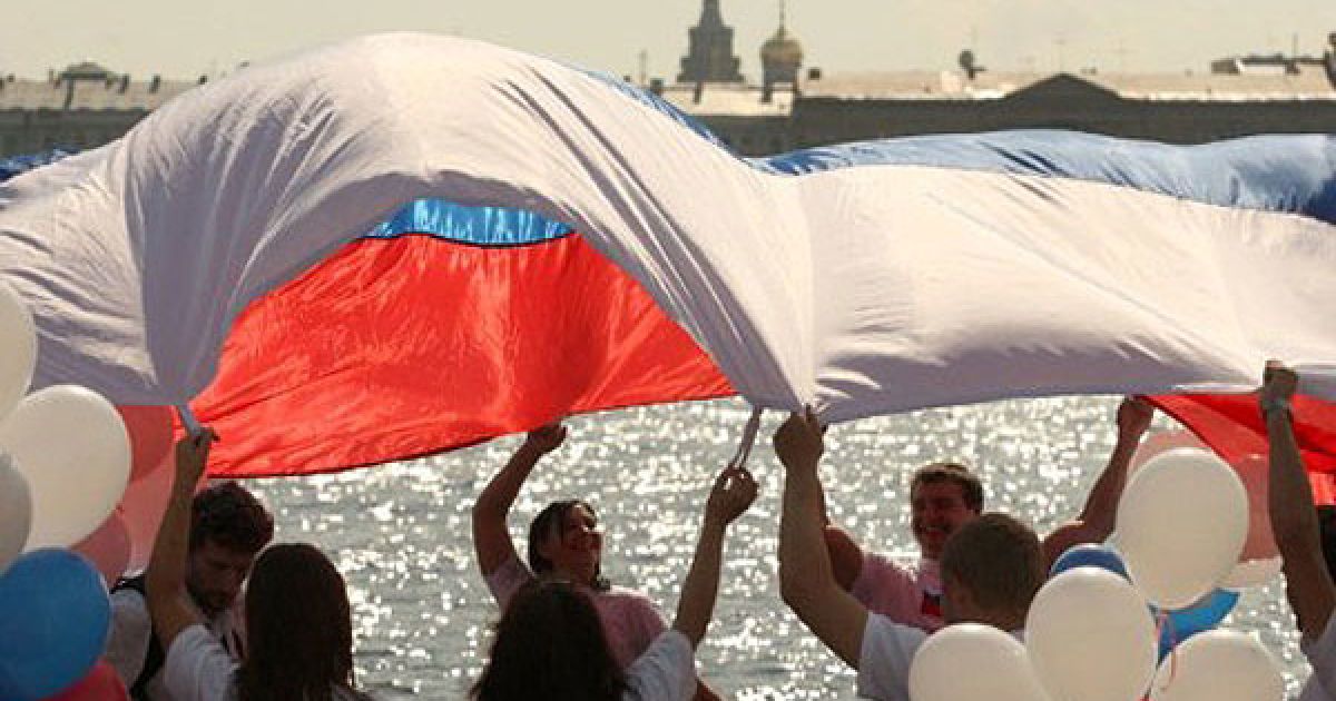 Росія, Санкт-Петербург. Люди розмахують величезним російським прапором під час святкування Дня прапора Росії у Санкт-Петербурзі. В Росії відзначили 20-річчя путчу 1991 року, який став початком розвалу СРСР. / © AFP