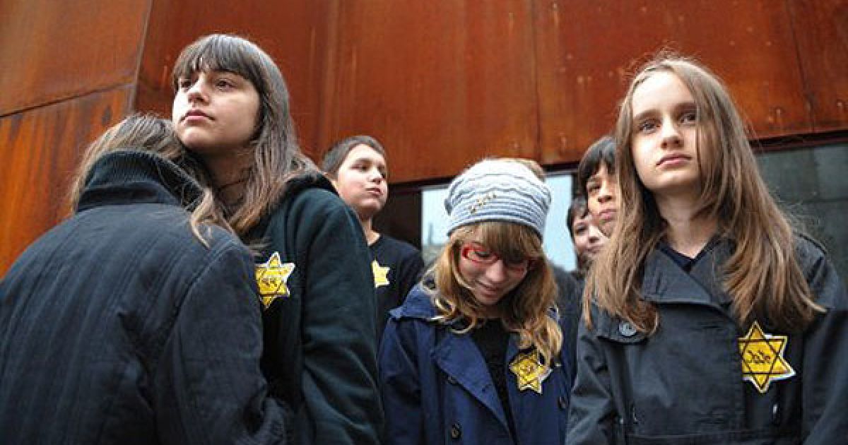 Румунія, Бухарест. Румунські діти із жовтими "єврейськими" зірками та написами німецькою "єврей" взяли участь у меморіальній церемонії на честь Дня пам&#039;яті жертв Голокосту в Бухаресті. / © AFP