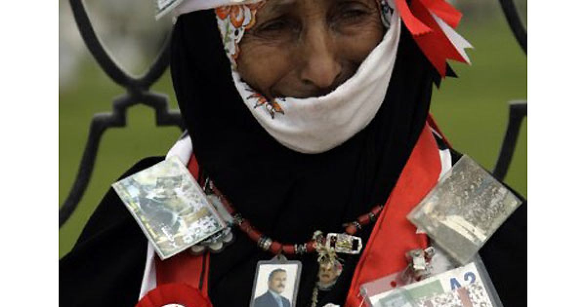 Ємен, Сана. Прихильниця президента Ємену Алі Абдалли Салеха тримає його фотографії та стрічки з національними кольорами під час мітингу на підтримку режиму Салеха після п'ятничної молитви у столиці країни Сана. / © AFP