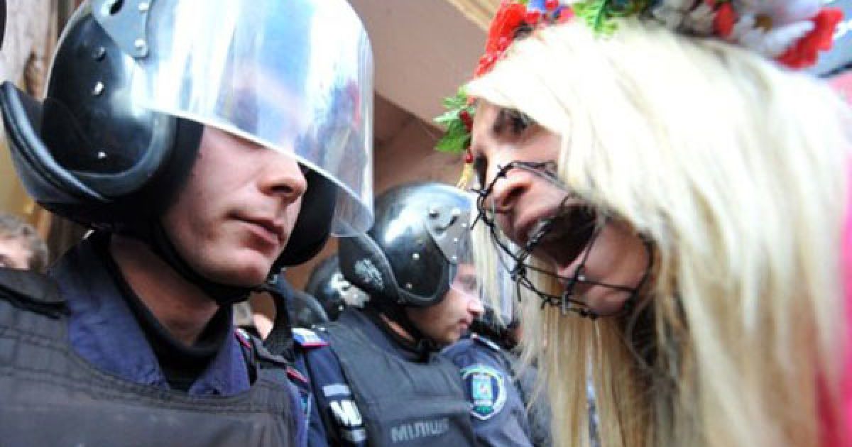 Україна, Київ. Активістка жіночого руху Femen кричить на міліціонера під час акції протесту "Кусючі цицьки" перед будівлею Печерського райсуду в Києві. Активісток Femen викликали в суд після топлес-протесту на НСК "Олімпійський" під час візиту на стадіон президента УЄФА Мішеля Платіні. / © AFP