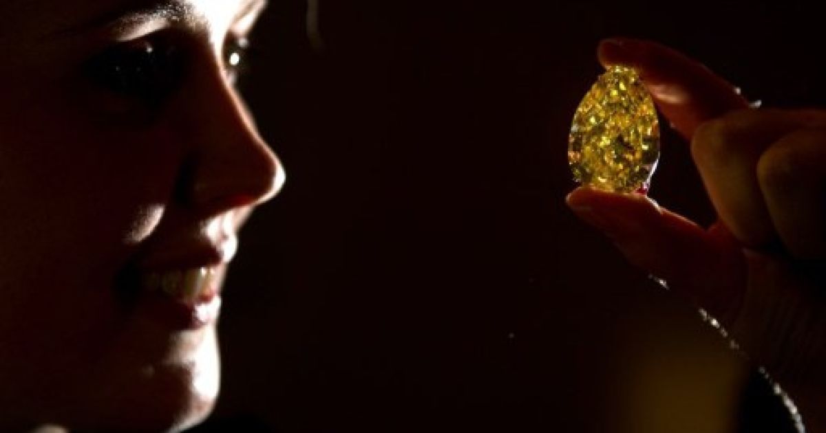 Великобританія, Лондон. Співробітник аукціону тримає діамант "Sun-Drop Diamond" ("Сонячна крапля") під час показу в аукціонному будинку Сотбіс у Лондоні. Діамант у 110,3 карата буде виставлений на аукціон в листопаді як частина колекції "Дивовижні коштовності" за стартовою ціною 11-15 млн дол. США. / © AFP