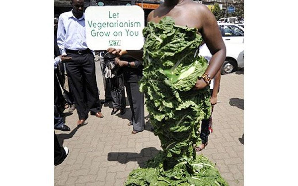 Кенія, Найробі. Модель Мішель Одьямбо з організації PETA ("Люди за етичне поводження з тваринами"), одягнена у довгу сукню, виготовлену цілком з листя салату, бере участь у акції протесту в Найробі. Мішель тримає в ручках табличку з написом "Хай вегетаріанство вкорінюється у вас". "Салатна леді" намагалась привернути увагу до страждань мільярдів тварин у світі, яких вирощують і вбивають для виробництва продуктів харчування. За версією РЕТА, споживання м&#039;яса, яєць і молочних продуктів є основною причиною зміни клімату та виснаження основних ресурсів, забруднення і навіть голоду у світі. / © AFP