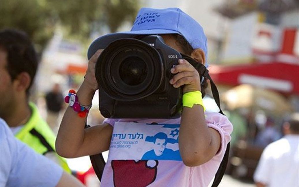 Ізраїль, Нетанія. Дівчинка тримає фотокамеру під час мітингу у Нетанії. Триває п&rsquo;ятий день 200-кілометрового урочистої ходи протесту проти захопленого у полон військового Гілада Шаліта. Маршрут учасників ходи прокладено з рідного міста Гілада Шаліта Міцпе-Хіла поблизу північного ізраїльсько-ліванського кордону до єрусалимської резиденції прем&rsquo;єр-міністра Ізраїлю Біньяміна Нетаньяху. Цього року виповнюється 4 роки з того часу, коли Шаліт був захоплений палестинськими бойовиками у секторі Газа. / © AFP