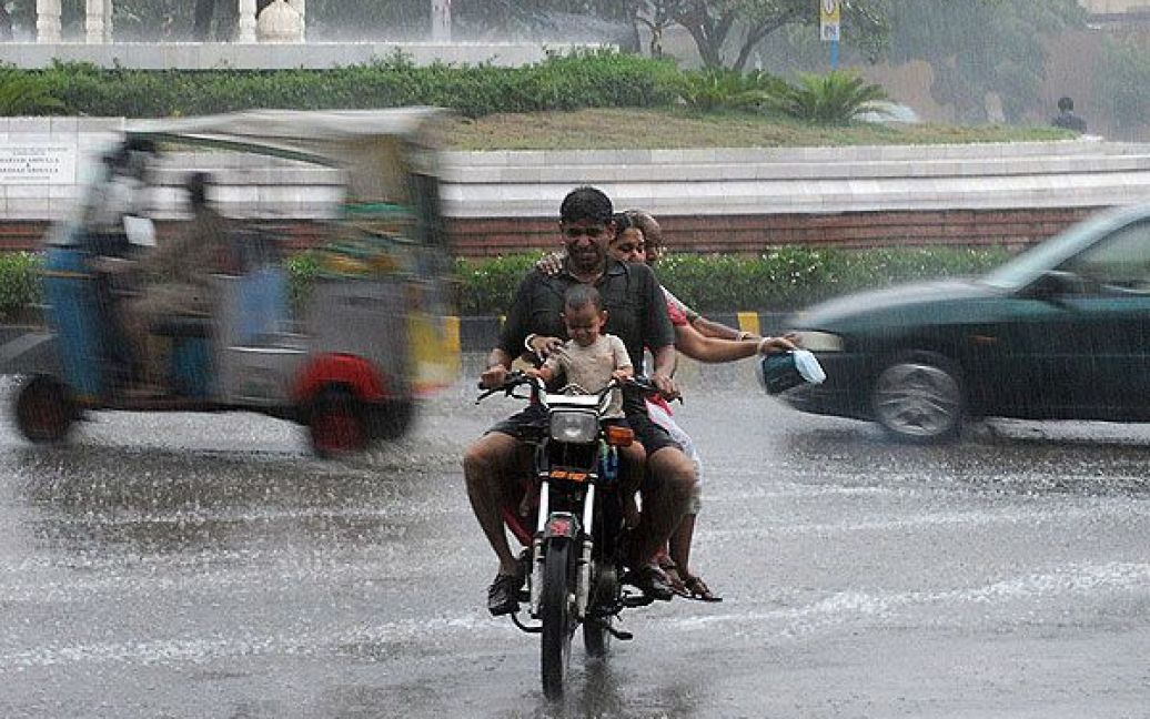 Пакистан, Карачі. Троє дорослих і дитина їдуть під дощем на мотоциклі вулицею міста Карачі. В результаті сильних дощів, які зазвичай тривають в країні з липня до вересня, у Пакистані іже загинули 10 людей. / © AFP