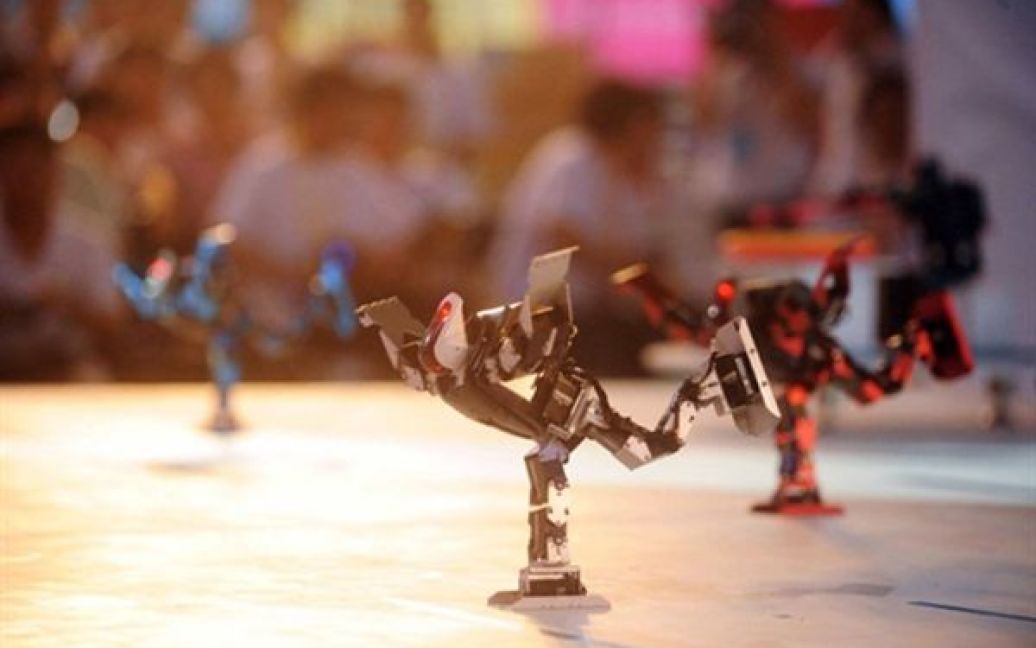 Учасники змагань та преса спостерігають тим, як роботи танцюють під час 10-го Китайського шоу роботів у Пекіні. Китай почав виходити з культурної та технологічної кризи, яка була спричинена вбивством чи від&rsquo;їздом науковців з країни після Культурної революції. / © AFP