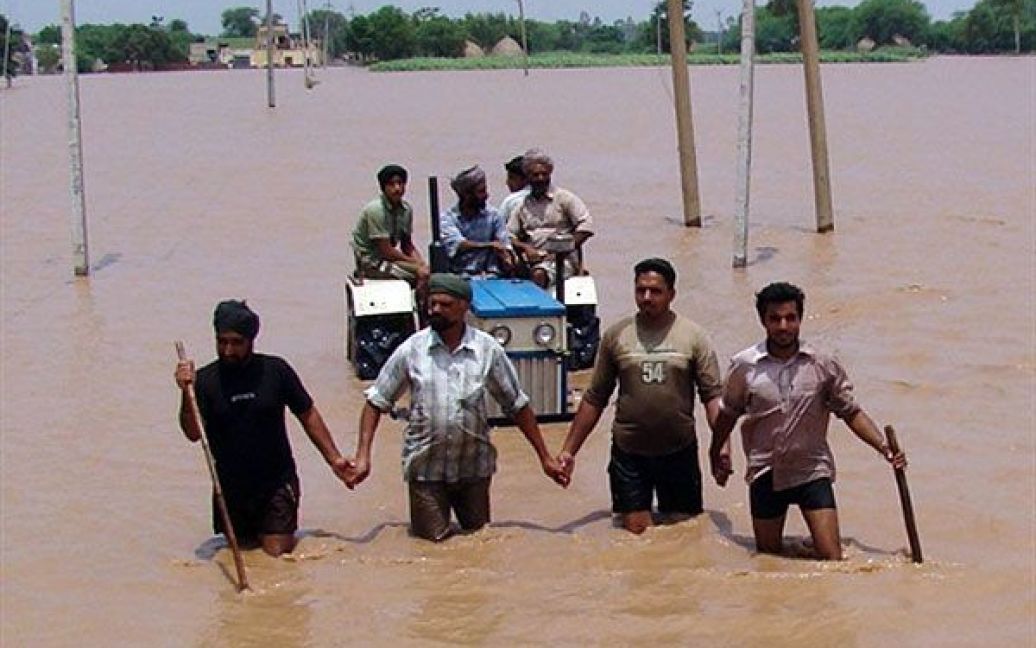 Індія, Патіали. Індійські чоловіки переправляються через затоплену територію поблизу Патіали у штаті Пенджаб. Сильні дощі частково затопили "житницю Індії", штат Пенджаб, понад 100 населених пунктів постраждали від повені. / © AFP