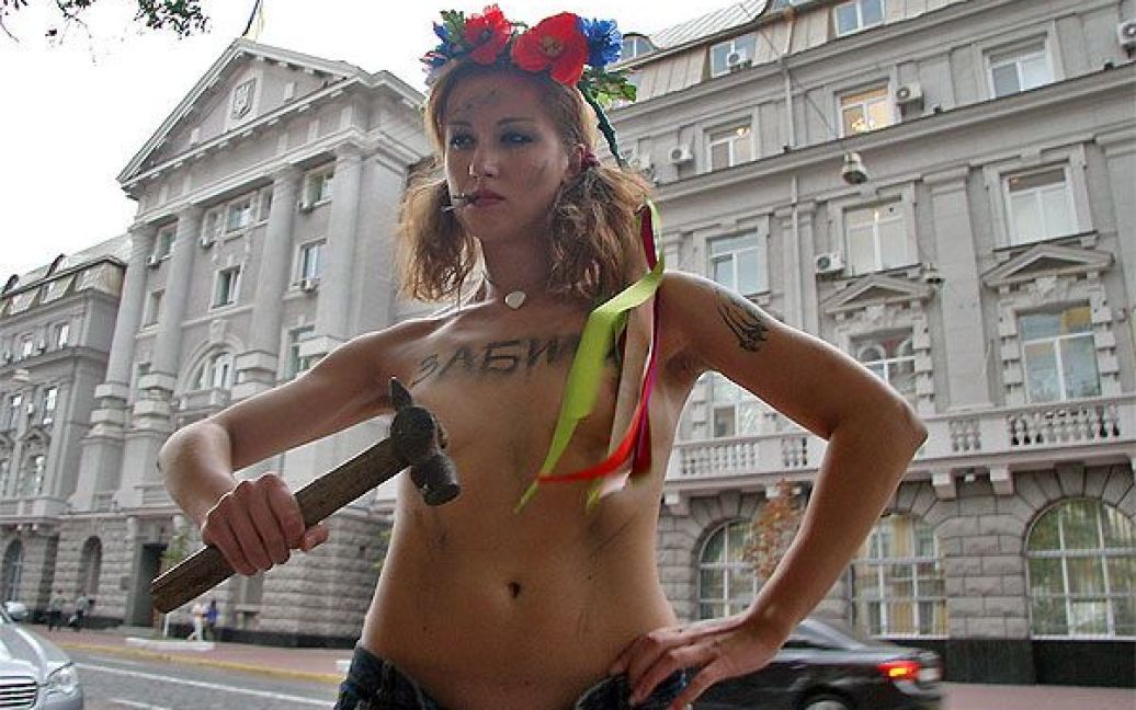 Активістка жіночого руху FEMEN з написом на грудях "Забили" вийшла до будівлі СБУ топлес, з молотком в руці та із цвяхами у роті. / © Жіночий рух FEMEN
