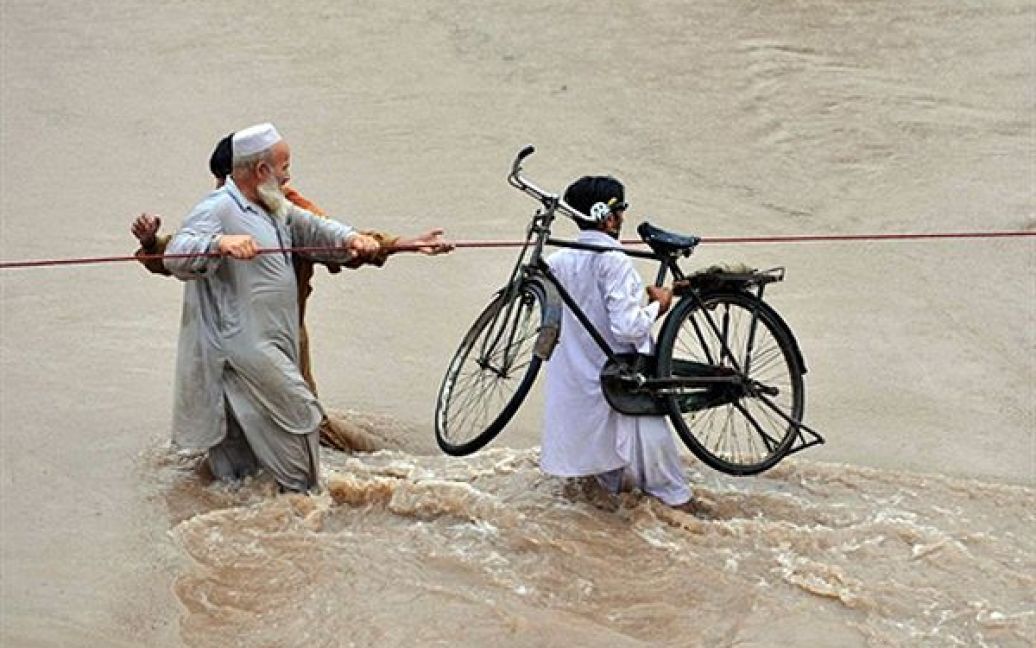 Чоловіки проходять затоплену місцевість у Новшері, Пакистан. Внаслідок повені у Пакистані вже загинули 34 людини. / © AFP