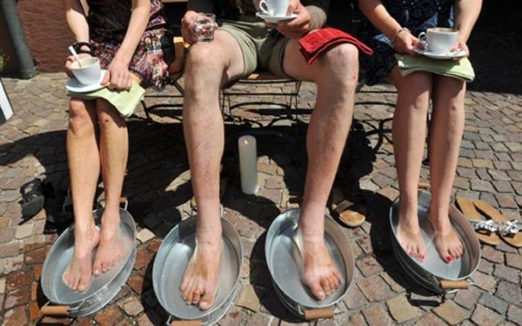 Власник кафе у Вальдкірхі, Німеччина, пропонує своїм відвідувачам охолодити ноги у крижаній воді. / © AFP