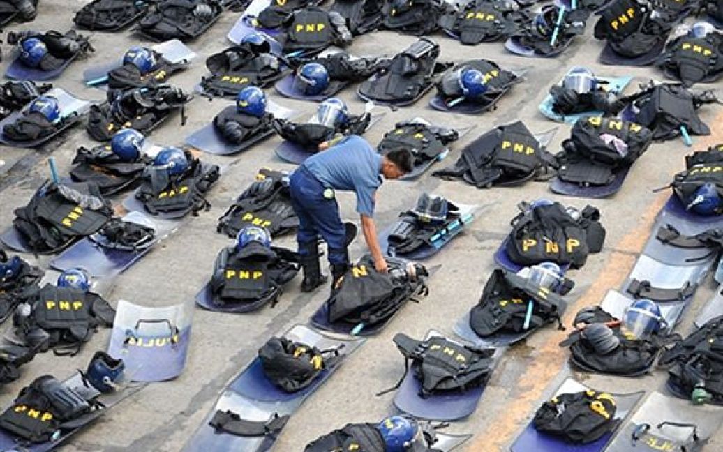 Офіцер філіппінської поліції перевіряє амуніцію перед зверненням президента Беніто Акіно до народу у Манілі. Тисячі людей вийшли на мітинг у Манілі з вимогою прийняти реформи, від яких відмовилася попередниця Акіно Глорія Арройо, та зупинити хвилю насильства у країні. / © AFP