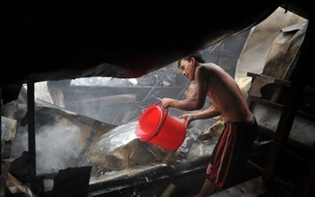 Чоловік намагається загасити пожежу у нетрях Маніли. Філіппінським пожежникам вдалося врятувати 150 родин, які жили у покинутих будинках. / © AFP