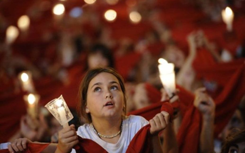 Люди тримають свічки та червоні хустки під час урочистого закриття фестивалю Сан-Фермін у Памплоні. Сан-Фермін, який проводиться вже кілька століть, залишається символом іспанської культури, незважаючи на численні протести захисників тварин. / © AFP