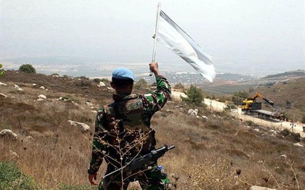 Ліван, Аддайсех. Індонезійський солдат з тимчасових сил ООН у Лівані розмахує прапором ООН перед ізраїльськими солдатами на кордоні, щоб спробувати вгамувати ситуацію. На кордоні Ізраїлю та Лівану війська двох країн вступили в перестрілку. Ізраїльський танк обстріляв ліванську територію після того, як кілька ракет або мін впали на півночі Ізраїлю, ліванці відповіли вогнем артилерії. Під обстріл з боку Лівану потрапили міста Метул і Кирьят-Шмона. / © AFP