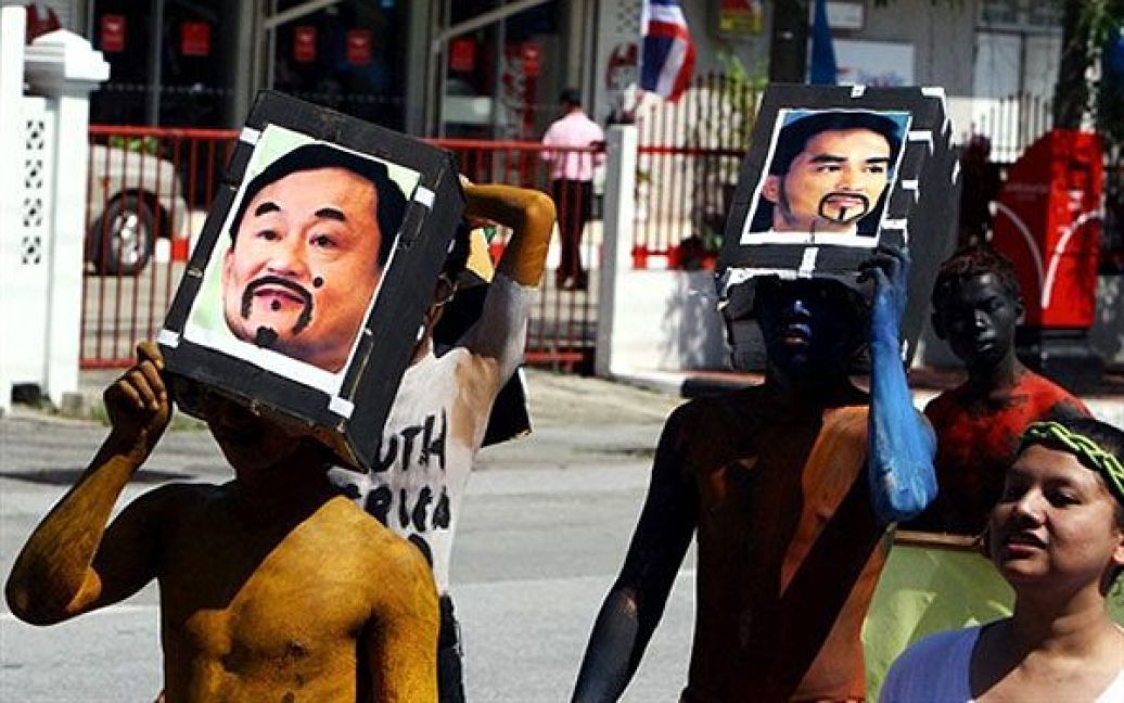 Таїланд, Наратхіват. Тайські студенти тримають над головами маски із фотографіями конкуруючих політиків: колишнього прем&#039;єр-міністра у вигнанні Такісна Чинавати і прем&#039;єр-міністра Абхісіта Веджадживи, під час участі у параді напередодні дня народження королеви Сірікіт, у південній провінції Таїланду. День народження королеви Сірікіт відзначатиметься по всій країні 12 серпня. / © AFP