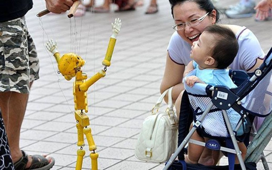 Тайвань. Тайванський ляльковод показує дитині маріонетку-скелет, щоб розсмішити малечу. / © AFP