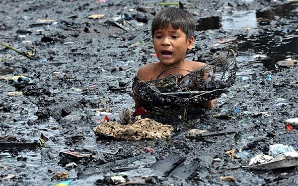 Філіппіни, Маніла. Дитина шукає речі у воді і намагається врятувати обвуглені предмети після гасіння пожежі у нетрях Малабон у Манілі. В результаті пожежі пожежні не змогли врятувати від вогню більше 300 будинків. Влада почала розслідування пожежі, в якій ніхто не постраждав. / © AFP
