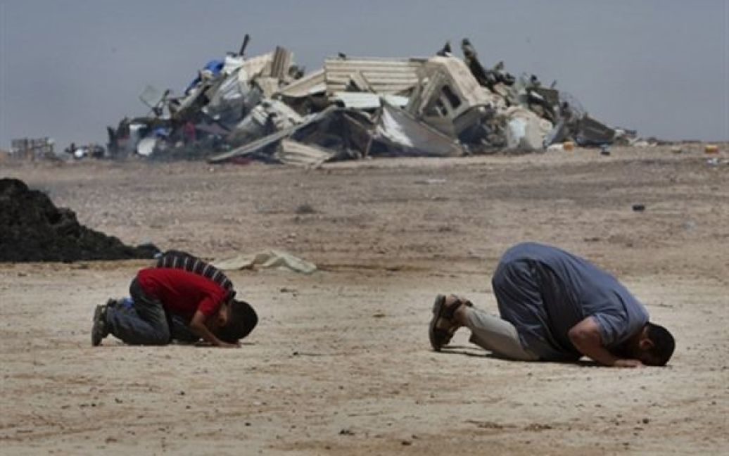 Бедуїни моляться на місці, де стояли їх будинки, які кількома днями раніше зруйнували солдати ізраїльської армії, у пустелі Негев. / © AFP