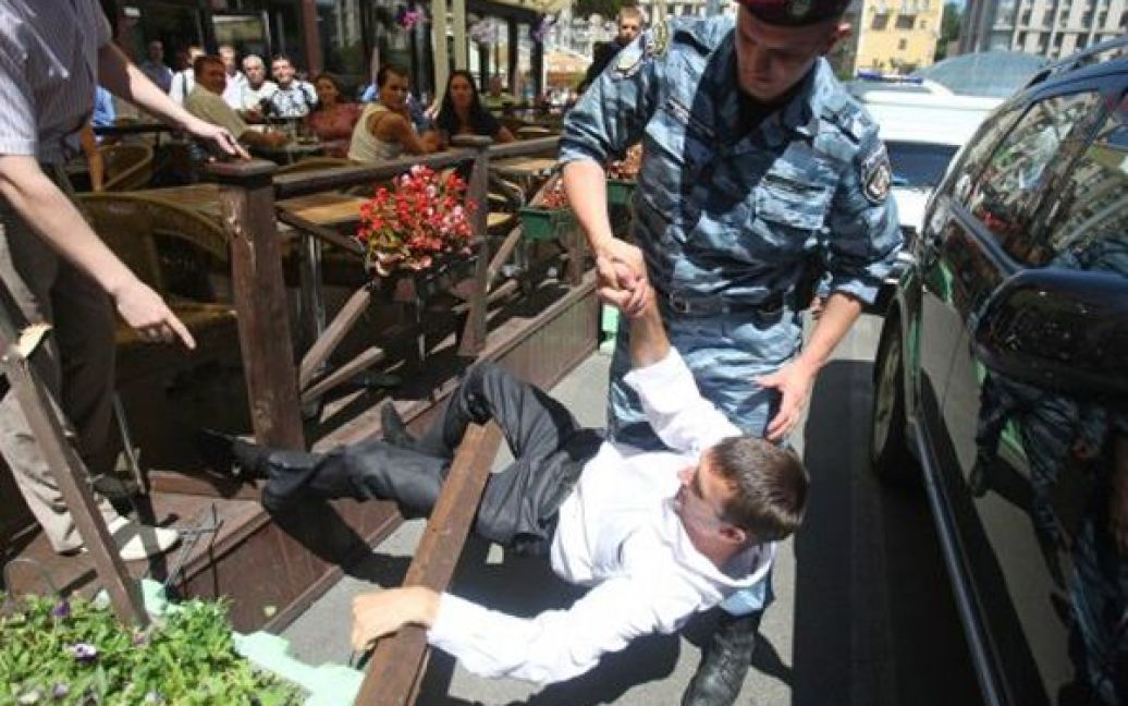 Боєць допомагає встати чоловікові, що впав, під час акції FEMEN на Майдані. / © УНІАН