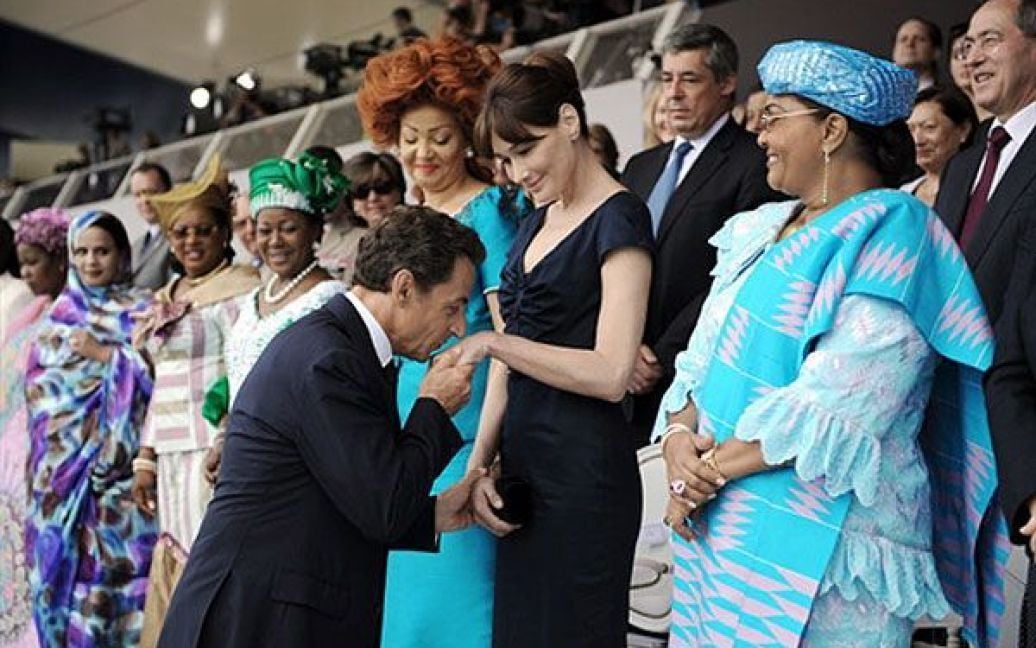 Франція, Париж. Президент Франції Ніколя Саркозі цілує руки своєї дружини, першої леді Франції Карли Бруні-Саркозі під час щорічного параду на честь Дня взяття Бастилії у Парижі. Поруч із президентським подружжям стоять дружина міністра оборони Кот-д&#039;Івуару Еліза Амані Н&#039;Гессана, перша леді Нігера Фаті Альзума Джибо Салу, перша леді Мавританії Текбер Мінт Ахмед, перша леді Малі Лоббо Траоре Траоре, перша леді Конго-Браззавіль Антуанетта Сассу-Нгессо, перша леді Камеруну Шанталь Бійя і перша леді Буркіна-Фасо Шанталь Компаоре. / © AFP