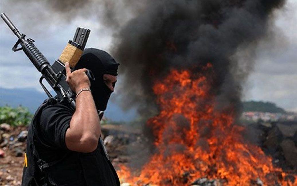 Гондурас, Тегусігальпа. Співробітник департаменту по боротьбі з наркотиками у Гондурасі спалює пакети з кокаїном. У Тегусігальпі спалили частину 500 кг кокаїну, вилученого у торговців наркотиками. / © AFP