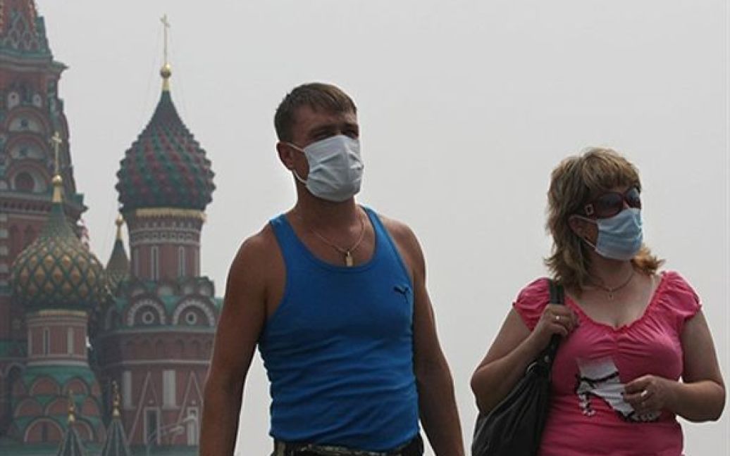 Туристи у захисних масках гуляють по Красній площі у Москві. Гості та жителі Москви змушені носити маски, щоб захиститися від смогу, який утворився внаслідок лісових пожеж. / © AFP