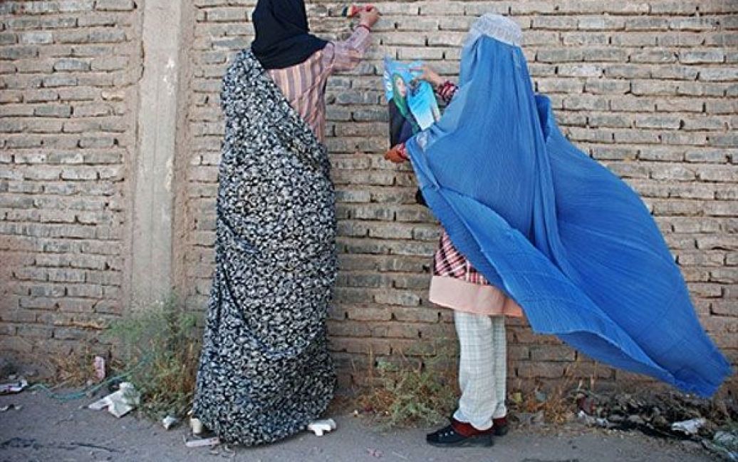 Афганістан, Герат. Афганські жінки вішають плакат жінки-кандидата на парламентських виборах у місті Герат. Парламентські вибори у Афганістані мають відбутись 18 вересня. / © AFP