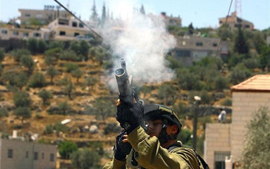 Віфлеєм. Ізраїльський солдат стріляє сльозоточивим газом по палестинських демонстрантах під час акції протесту проти ізраїльського розділового бар&#039;єру на Західному березі Бейт-Джало у Віфлеємі. Ізраїльські та палестинські чиновники заявили, що вони розпочнуть непрямі мирні переговори протягом кількох днів, після того, як Ліга арабських держав затвердить запропонований США план виходу з цієї ситуації "глухого кута". / © AFP