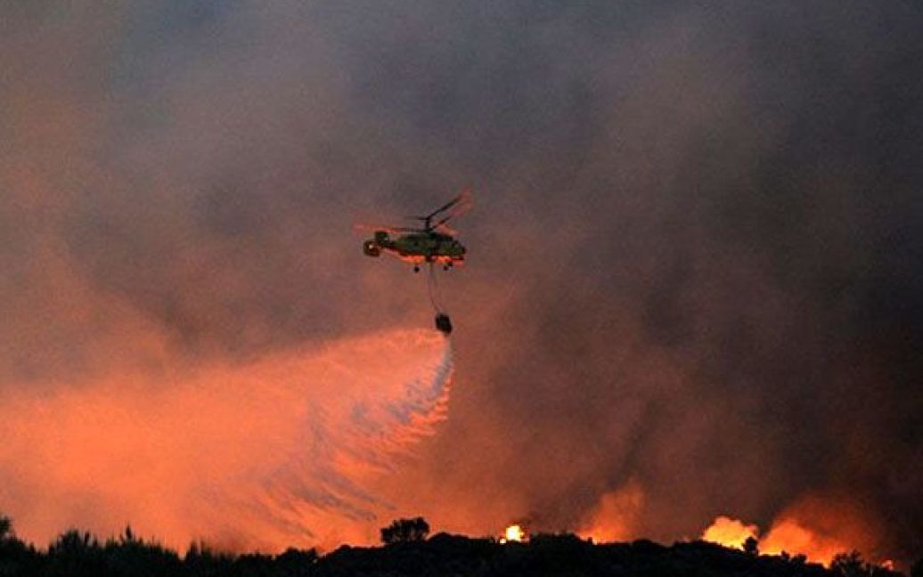 Португалія, Сан-Педру-ду-Сул. Гелікоптер виливає воду, щоб загасити лісову пожежу у Карвальялі неподалік від Сан-Педру-ду-Сул у центральній Португалії. Майже тисяча пожежних були мобілізовані на боротьбу з лісовою пожежею. / © AFP