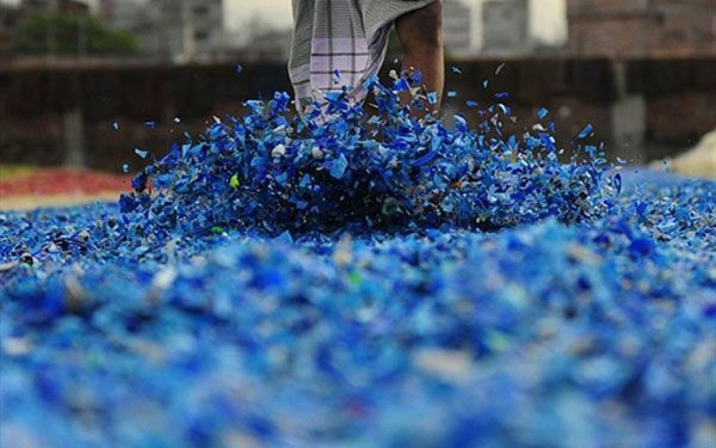 Бангладеш, Дакка. Робочий розподіляє на землі ногами шматки переробленого пластику. Бангладеш є однією з найбідніших країн на планеті, тут майже 40 відсотків від 144-мільйонного населення живуть менш ніж на 1 долар на день. / © AFP
