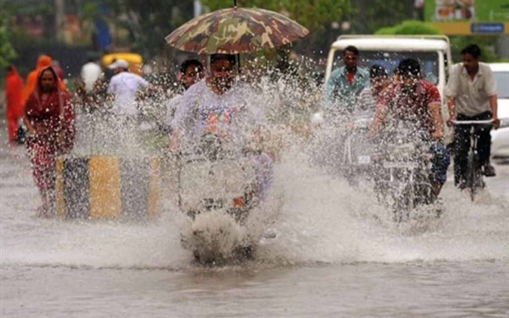 Чоловіки їдуть по вулиці, яку затопило під час зливи, у Армітсарі. Через сильні дощі у кількох індійських штатах сталася повінь. / © AFP