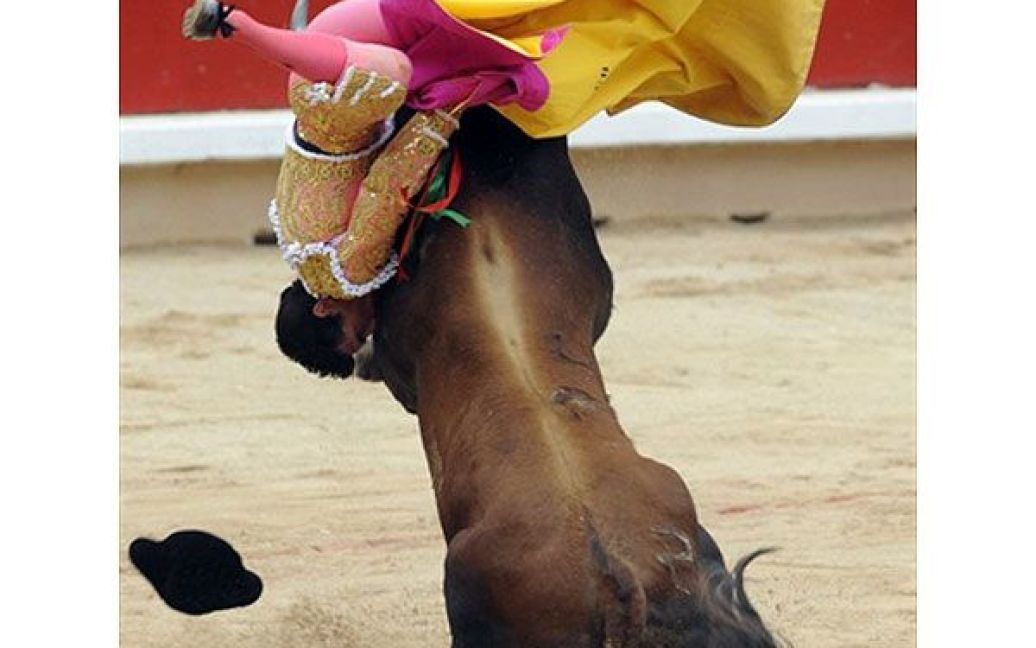 Іспанія, Памплона. Іспанського матадора Франциско Марко піднімає на роги бик зі стайні "Себада Гаго" під час кориди. У місті Памплона проходять щоденні бої биків на честь фестивалю Сан-Фермін. / © AFP