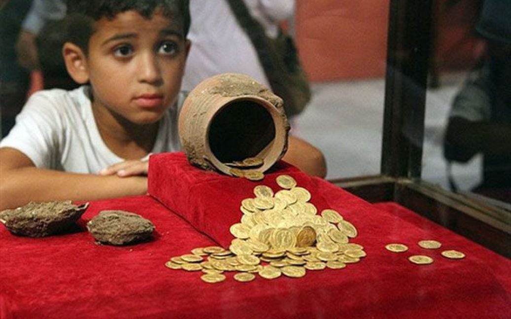 Єгипет, Каїр. Хлопчик роздивляється стародавні монети на виставці "Монети крізь століття" у Єгипетському музеї у Каїрі. На виставці представлені колекції монет, які належали до різних історичних періодів, в тому числі, рідкісні золоті, срібні та бронзові монети, а також інші предмети антикваріату. / © AFP
