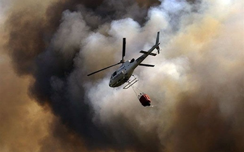 Іспанія. Гелікоптер несе воду, щоб загасити лісову пожежу у місті Куаледро поблизу Оуренса. / © AFP