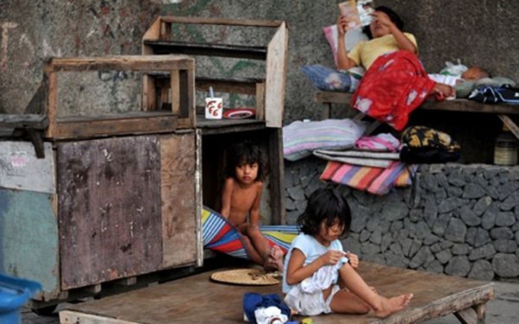 Родина, яка живе у дерев&rsquo;яному візку, відпочиває біля своєї "оселі" на окраїні Маніли. Представник уряду Філіппін заявив, що бідні родини будуть отримувати матеріальну допомогу у рамках державної програми боротьби із бідністю. / © AFP