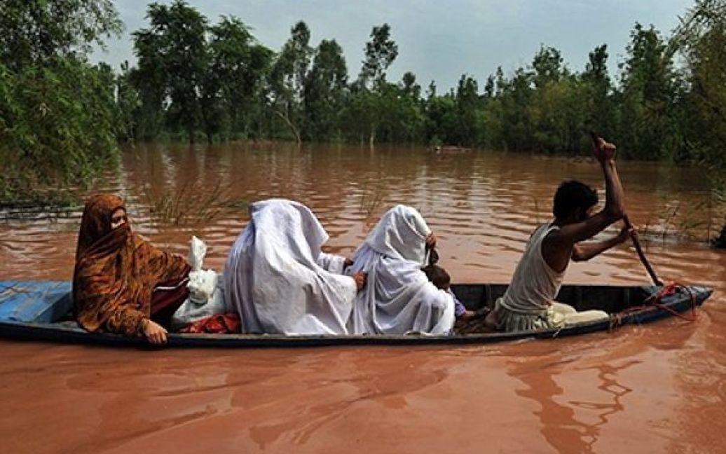 Волонтер допомагає евакуювати людей з затопленого селищі на сході Пакистану. Внаслідок повеней та зсувів, які були викликані сильними зливами, у Пакистані загинули 320 людей. / © AFP