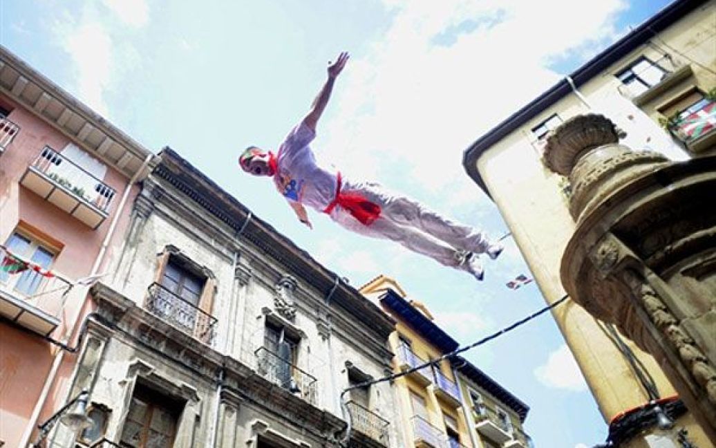 Іспанія, Памплона. Чоловік стрибає з фонтану під час свята "Chupinazo", щоб відзначити початок фестивалю у Сан-Ферміні. Щорічний фестиваль у Памплоні на півночі Іспанії є символом іспанської культури, щороку, незважаючи на засудження з боку захисників прав тварин, фестиваль приваблює тисячі туристів. / © AFP