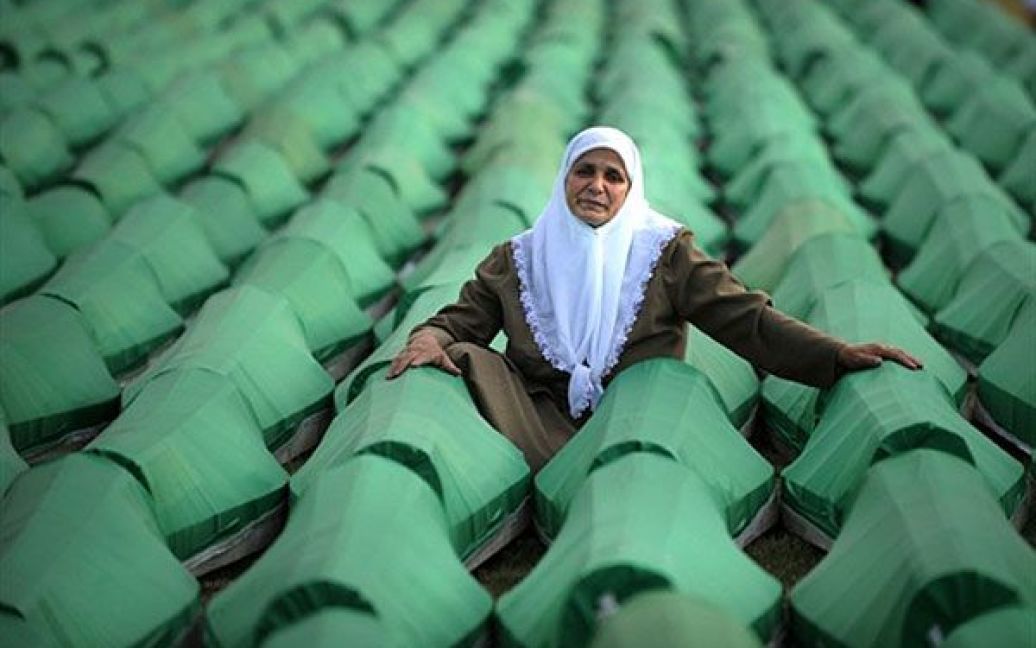 Боснія і Герцеговина, Поточарі. Боснійська жінка сидить поруч із десятками трун з тілами жертв різанини у Сребрениці 1995 року. У меморіалі Поточарі неподалік від Сребрениці на 15-ту річниця різанини у Сребрениці відбулась церемонія масового перепоховання більше 775 тіл, виявлених у братській могилі у східній Боснії. Майже 8000 чоловіків і хлопчиків з анклаву були схоплені і потім убиті боснійськими сербами протягом перших днів після падіння Сребреніци 11 липня 1995 року. Жертви були розстріляні і поховані у братських могилах. У пам&rsquo;ятній ході до Сребрениці цього року взяли участь більше 5 тисяч людей. / © AFP