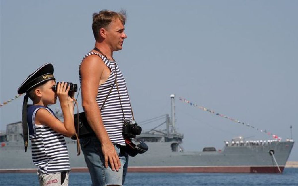 Чоловік із сином спостерігають за репетицією параду до Дня ВМФ РФ. / © PHL.com.ua