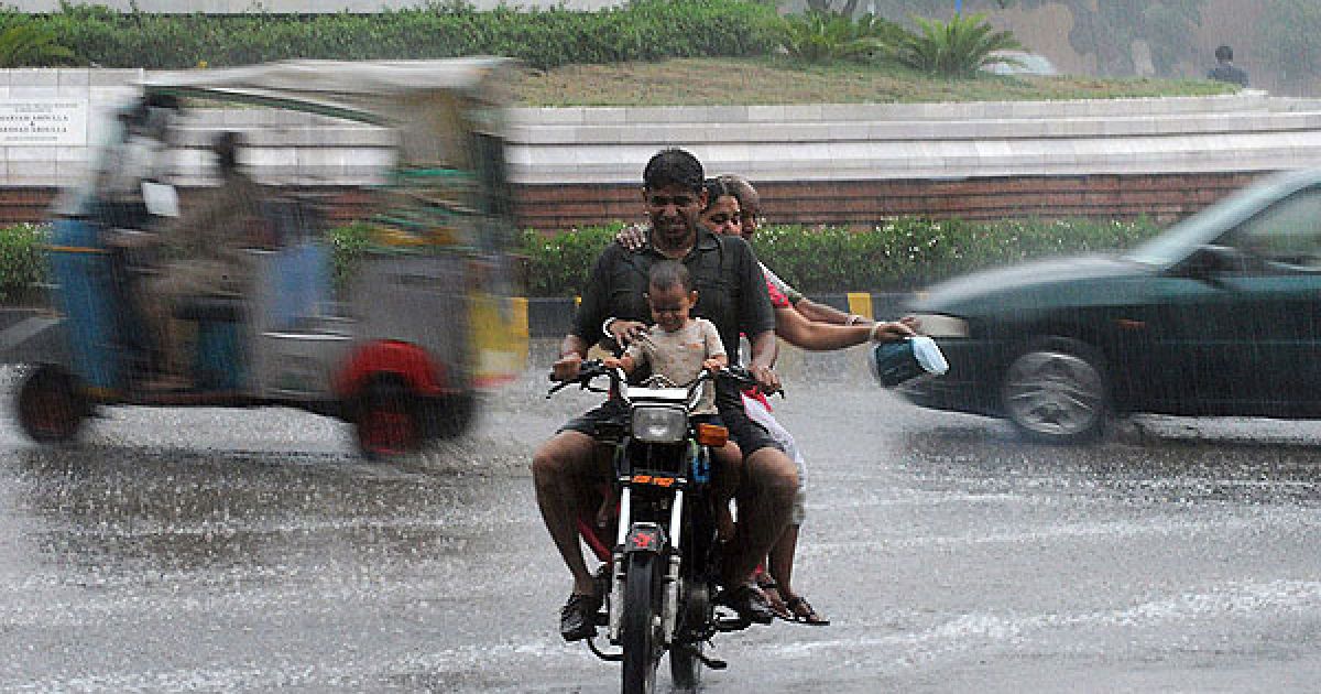 Пакистан, Карачі. Троє дорослих і дитина їдуть під дощем на мотоциклі вулицею міста Карачі. В результаті сильних дощів, які зазвичай тривають в країні з липня до вересня, у Пакистані іже загинули 10 людей. / © AFP
