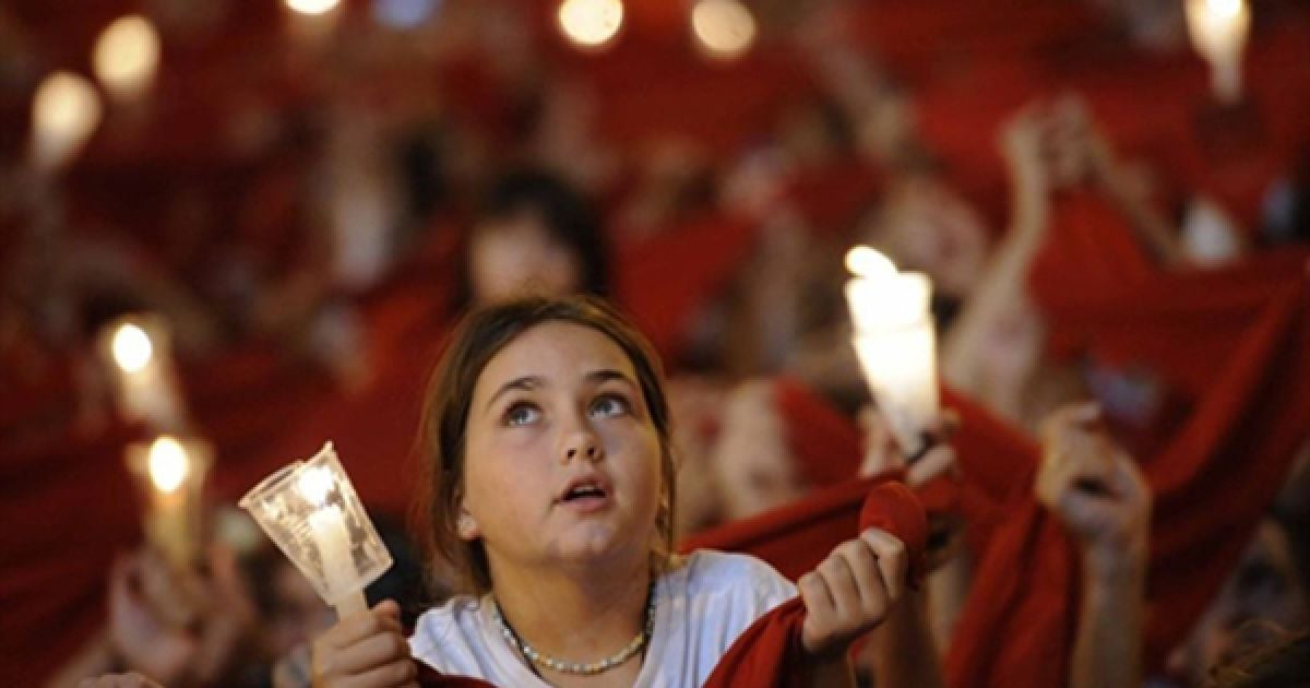 Люди тримають свічки та червоні хустки під час урочистого закриття фестивалю Сан-Фермін у Памплоні. Сан-Фермін, який проводиться вже кілька століть, залишається символом іспанської культури, незважаючи на численні протести захисників тварин. / © AFP