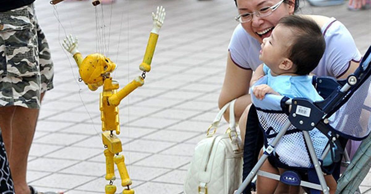 Тайвань. Тайванський ляльковод показує дитині маріонетку-скелет, щоб розсмішити малечу. / © AFP