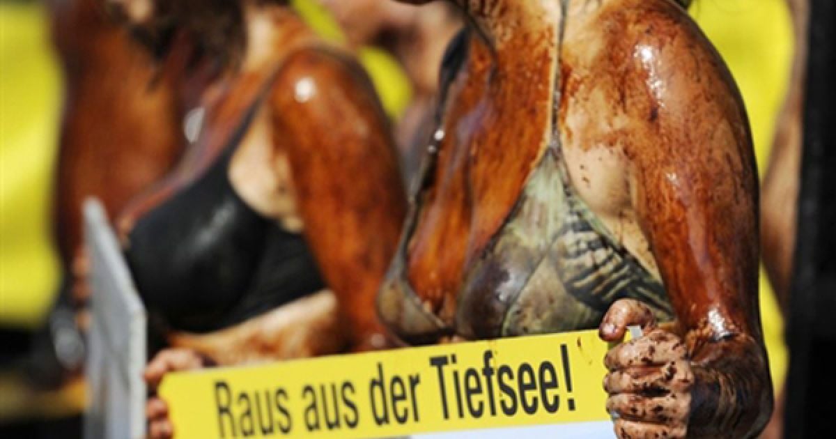 Берлін. Активістки організації Greenpeace, облиті нафтою, тримають транспаранти з написами: "Ні нафті у морі!" під час своєї акції протесту проти дій компанії ВР з ліквідації розливу нафти у Мексиканській затоці. Нещодавно ВР нарешті вдалося зупинити вилив нафти у море. / © AFP