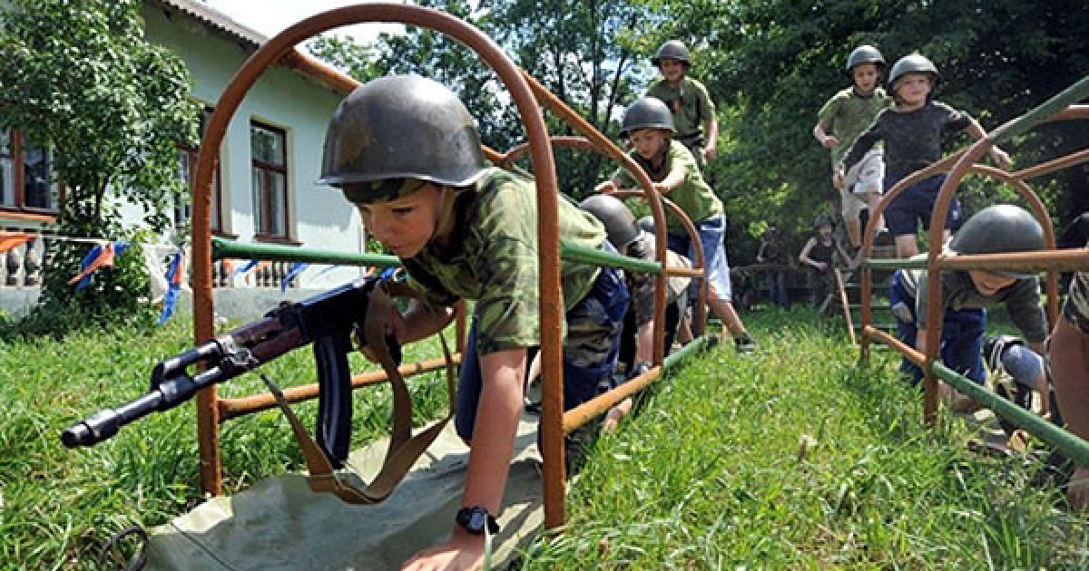 Білорусь. Білоруські діти з дерев'яними кулеметами проходять смугу перешкод у військовому літньому таборі у селі Жодіно, поруч із Мінськом. Влітку діти проводять кілька тижнів у подібних таборах. / © AFP