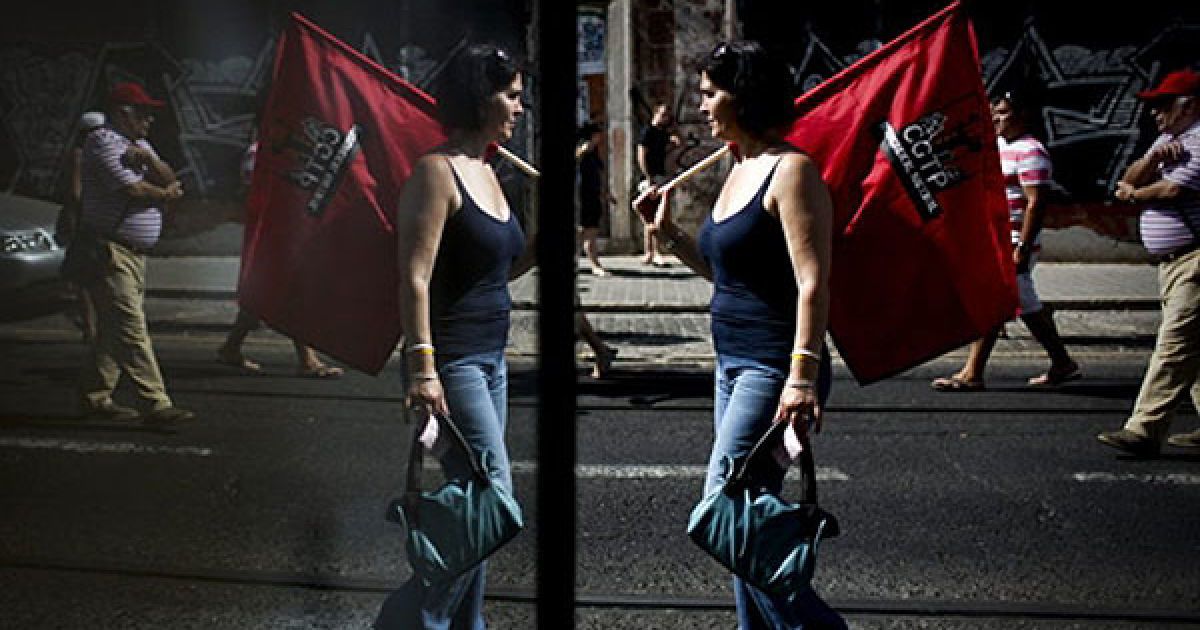 Португалія, Лісабон. Жінка з прапором бере участь у багатотисячному марші протесту, учасники якого виступили проти урядових заходів жорсткої економії. Марш протесту у Лісабоні організувала найбільша профспілка Португалії Португальська Генеральна конфедерація робочих. / © AFP