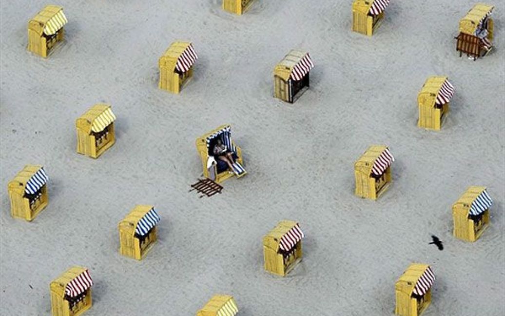 Німеччина, Травемюнде. Люди сидять у плетених стільцях на морському пляжі біля північного міста Травемюнде. Поки у Німеччині утримується температура не вище 16 градусів за Цельсієм, пляжі стоять майже порожні. / © AFP