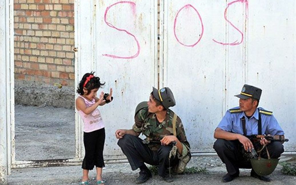 Киргизстан, Ош. Дівчинка розмовляє з киргизькими поліцейськими, які здійснюють обшук у будинках етнічних узбеків у місті Ош. Влада Киргизстану заявила, що більше половини з тих, хто втік до сусіднього Узбекистану під час кривавих міжетнічних зіткнень, повернулися до країни. / © AFP