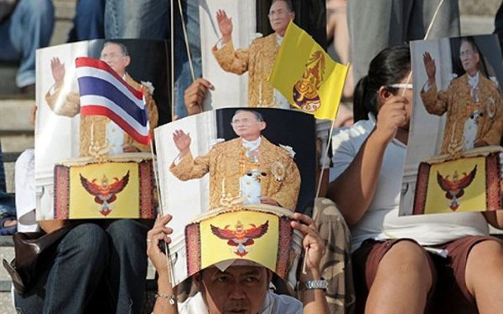 Банкок. Учасники проурядового мітингу закриваються від сонця портретами тайського короля Пхуміпона Адульядета. Прем’єр-міністр Таїланду повідомив, що він готує договір з опозицією, який дозволить закінчити акції протесту. / © AFP